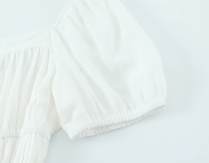 Détail rapproché des manches bouffantes blanches et des poignets élastiques froncés