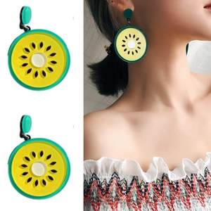 Detailed view and model try-on of green acrylic kiwi slice dangle earrings