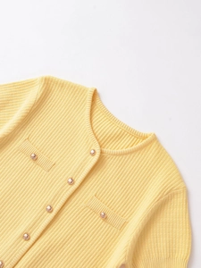Detail of yellow ribbed knit cardigan with gold buttons and small front pockets