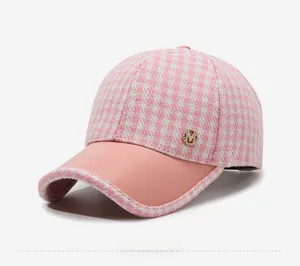 Détail de la casquette pied-de-poule rose avec logo M et visière en cuir mat