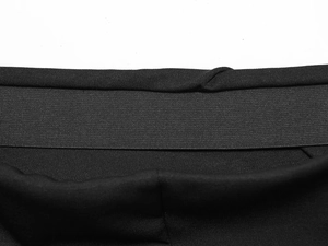 Close-up of wide elastic waistband on a black A-line minimalist twist commute skirt