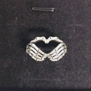 Detail of gothic silver ring featuring two skeleton hands forming a heart shape
