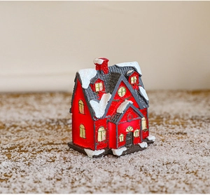 Detailed view of a miniature red Christmas house model with snow decor on a winter base