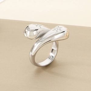 Macro detail of silver wrap ring with star-cut stones and teardrop design on textured surface