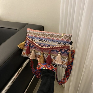 Detail of bohemian woven crossbody bag with colorful tassels and patterned wide strap