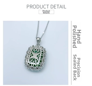 Macro shot of silver necklace pendant with green stone and hollow floral pattern back