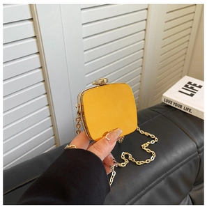 Close-up of golden hard shell evening clutch with a shiny finish and metal chain strap