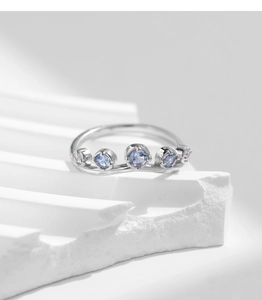 Macro shot of silver ring with blue gemstones in wave setting on stone base