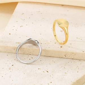 Close-up of gold and silver textured sunflower rings on a beige stone display block