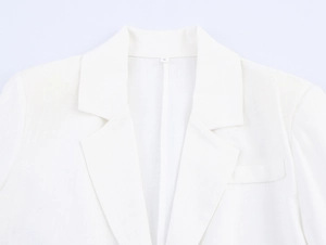 Detail of white lapel suit jacket showing linen texture and chest pocket design