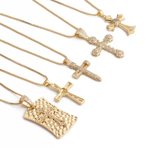 Close-up of five gold zircon cross pendant necklaces with various textures and designs