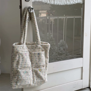 Detailed view of plush tote bag with colorful mosaic patterns and four front buttoned pockets