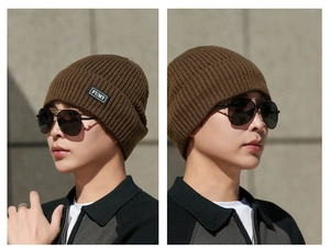 Detail of dark brown knitted beanie with ribbed texture and FUMY logo patch on the cuff