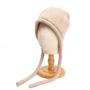 Dettaglio del cappello in lana beige con lacci lunghi e trama a coste in maglia fine