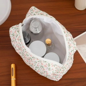 Detail of floral makeup bag with heart zipper on wooden table showing spacious inner storage