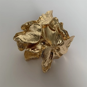 Macro shot of gold leaf cuff bracelet showcasing detailed stripe texture and matte finish