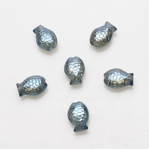 Macro detail of blue-gray fish-shaped glass beads with iridescent scales and texture
