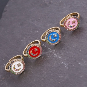 Detail of colorful enamel star and moon rings with zircon inlay on a dark stone surface