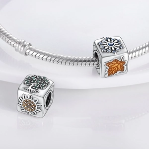 Détail macro de perles cubes avec motifs naturels et flocons sur un bracelet en argent poli