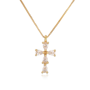Macro shot of gold cross pendant with pear-cut cubic zirconia stones on a box chain