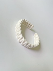 Detail of white handmade woven cotton cord bracelet with complex bohemian knot patterns