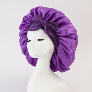 Detailed view of dark purple satin sleep cap featuring a large bow and silk texture