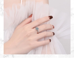 Close-up of a silver ring with a round zircon stone on model's finger with white tulle