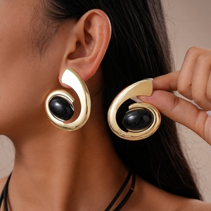 Chunky gold spiral earrings with large black oval gemstone on model portrait