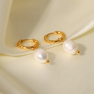 Detailed view of twisted gold hoop earrings with natural freshwater pearls on satin