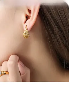 Macro-opname van gouden druppeloorbellen met onregelmatige textuur bij een model