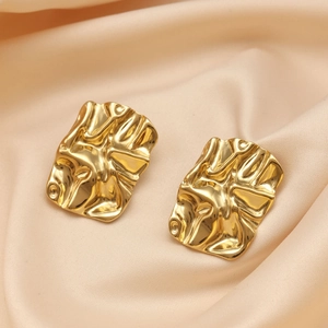 Macro shot of 18K gold plated earrings with irregular wrinkled texture on satin