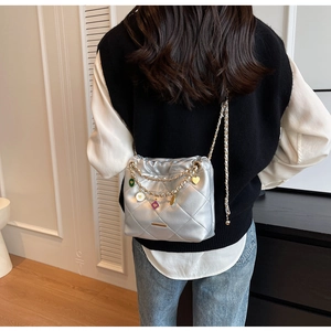 Detail of silver quilted bucket bag featuring colorful heart charms and chain strap