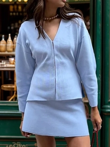 Detail of light blue knit two-piece set featuring a V-neck cardigan and matching mini skirt