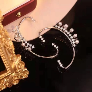 Detail of elegant ear cuff with pearls and crystals on a reflective black surface