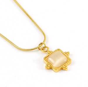 Gros plan sur collier chaîne serpent dorée avec pendentif carré et pierre œil de chat