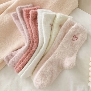 Dettaglio di calze di peluche morbide con delicato ricamo a cuore in vari colori pastello
