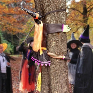 Outdoor Halloween tree hugging witch decoration with colorful limbs and orange hair
