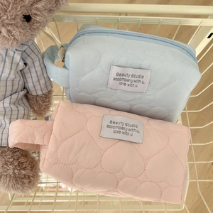 Detail view of quilted heart cosmetic bags in light blue and pink with soft side handles