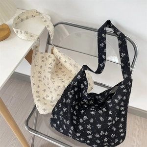 Détail de sacs fourre-tout en toile florale noir et blanc accrochés à une chaise