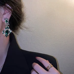 Elegant emerald green drop earrings with brilliant crystals on a model's ear