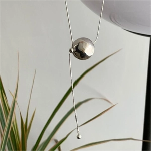 Minimalist 925 sterling silver ball pendant necklace with thin chain on neutral background