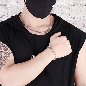 Close-up of polished silver Cuban chain necklace and bracelet set worn by model