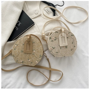 Detailed macro view of woven straw texture and delicate pink floral embroidery on round bags