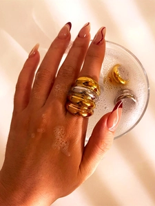 Close-up of a two-tone wavy layered ring in gold and silver finish on a model's hand