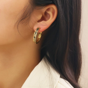 Gold round earrings for women with colorful zircon stones worn on model ear