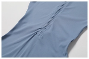 Détail du zip frontal et des coutures plates sur le body de yoga bleu brumeux