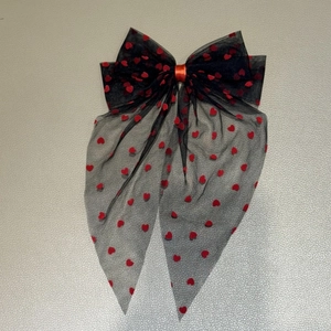 Detail of black mesh bow hair clip with red flocked hearts and long trailing ribbons