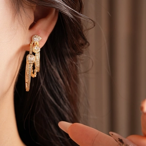 Close-up of golden triple-layered oval earrings set with sparkling zircon on a model