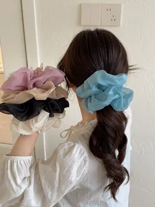 Dettaglio di elastici scrunchie giganti in organza colorata con trama a rete soffice e leggera