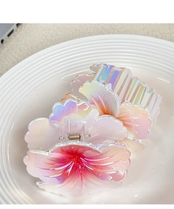 Close-up of two gradient pink plumeria hair claws with pearl finish on white plate